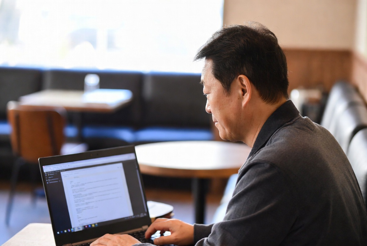 카페에서 중년 남성이 노트북으로 주택연금 관련 문서를 확인하는 모습