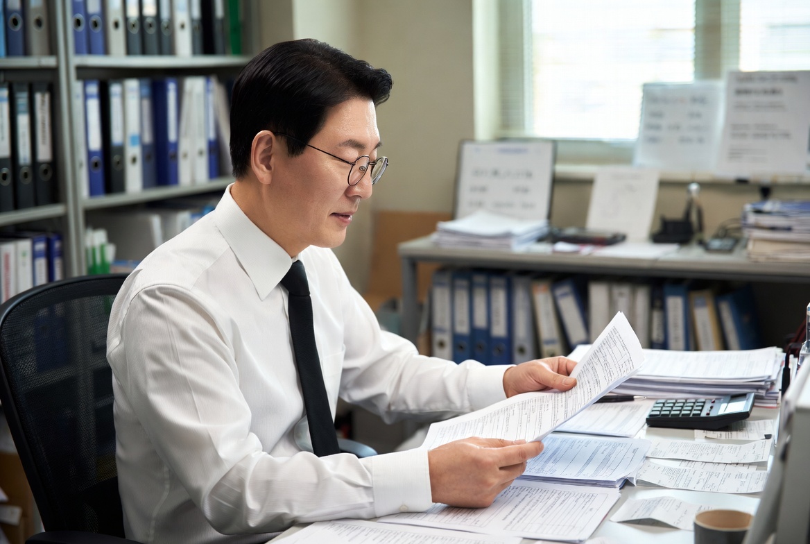 세무사 상담실에서 중년 남성이 영수증과 서류를 검토하는 모습