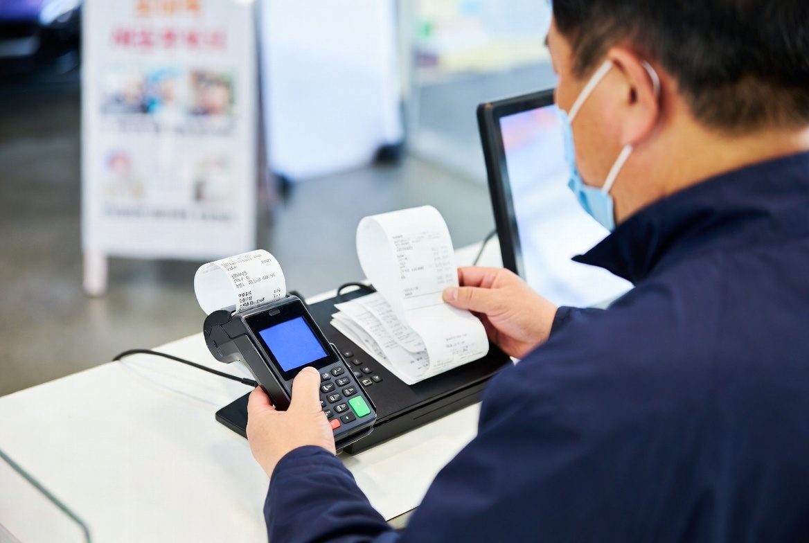 소상공인 사업장 카운터에서 영수증을 확인하는 40대 남성 사장